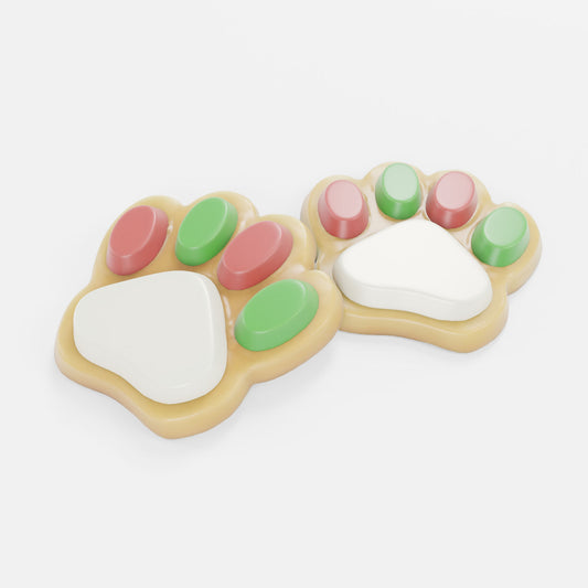 Two paw-shaped treats decorated with white, pink, green, and beige icing, set against a plain light gray background.