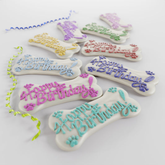 Assorted 5-inch Big Bone dog cookies with white yogurt icing and colorful celebration messages